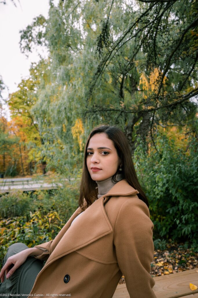 outdoor shot of beautiful lady wearing a brown coat posing for the camera.